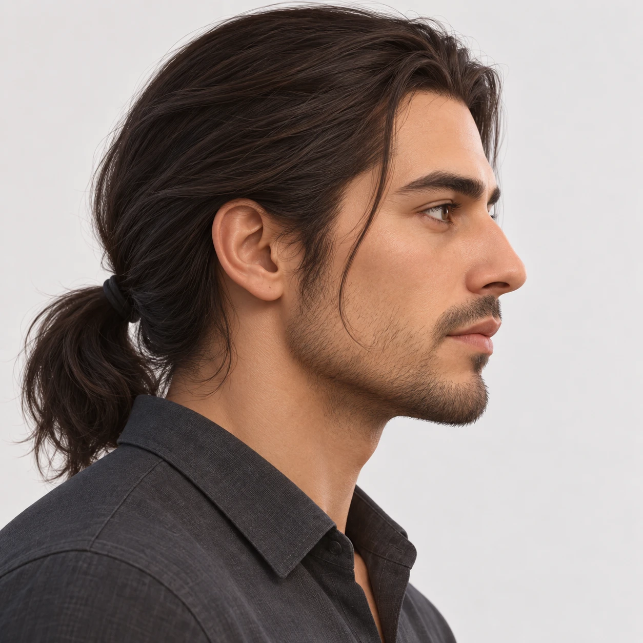 Illustration of one man with long dark hair gathered into a low ponytail and a charcoal shirt, his head and shoulders seen in full profile from the side with his gaze level ahead and a calm closed-mouth expression, closely cropped so the head and shoulders fill most of the picture, hands not visible, a plain pale background behind him, the lower edge left as empty background with nothing written on it (soft 3D)